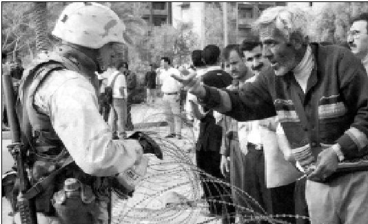 Amerikanske soldater holder irakere bag pigtråd